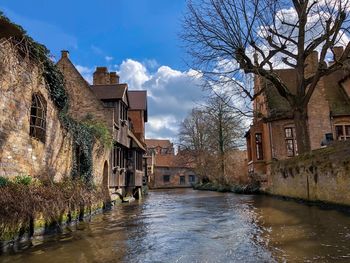 River amidst houses and buildings against sky