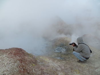 Side view of man photographing misty land