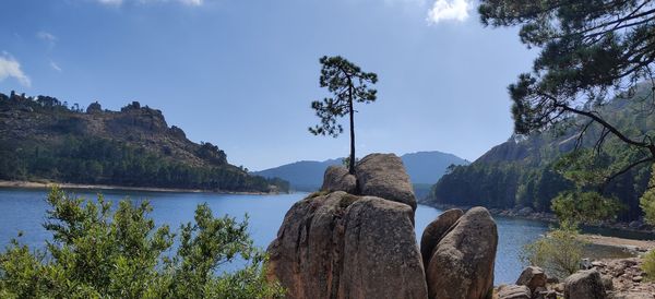 Panoramic view of rocks by lake against sky