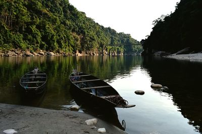 Boats moored on lake against clear sky