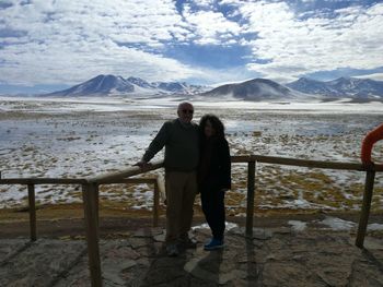 Couple standing against railing and sky