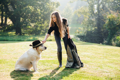 Woman with dog on grass against trees