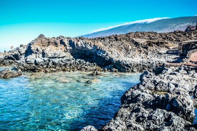 Scenic view of rocks on shore against sky