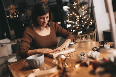 Good mood woman in a cozy environment wrapping gifts for christmas, stylish decoration, vintage