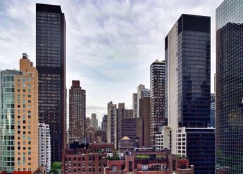 Buildings in city against cloudy sky