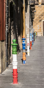 Colorful bollards on street by building