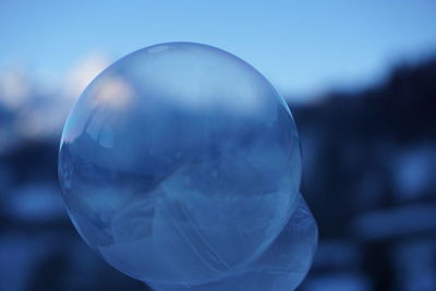 Close-up of crystal ball against sky