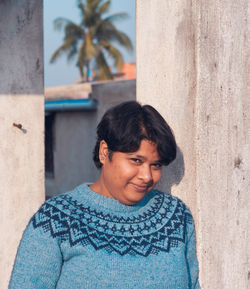 Portrait of smiling young woman against wall