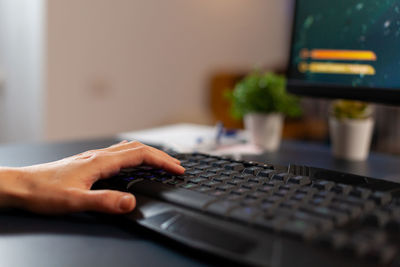 Cropped hand of woman playing game at home