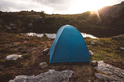 Tent near a lake against cloudy sky and sunset