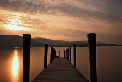 Wooden pier on sea against sky during sunset