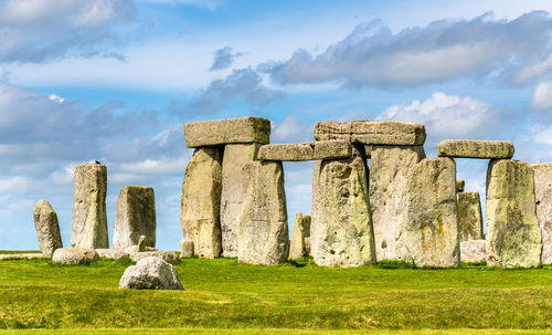 Stone structure on field against cloudy sky