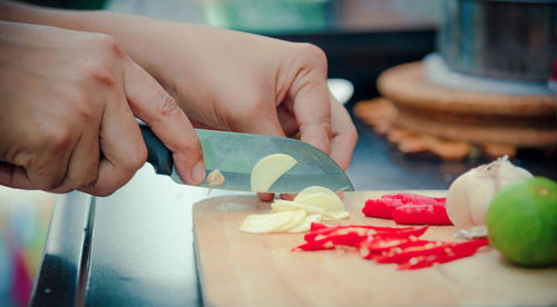 Cropped hands of woman cutting garlic in kitchen