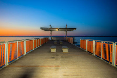 Pier over sea against sky during sunset