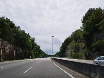 Road amidst trees against sky