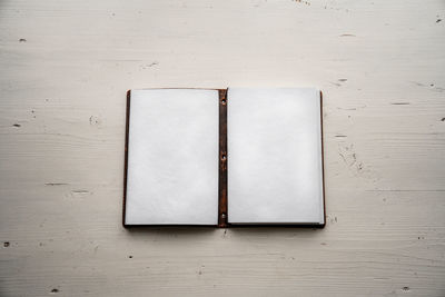 Directly above shot of open book on table against white wall