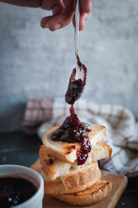 Close-up of toasted slices of bread with homemade strawberry jam dripping from spoon