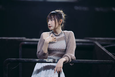 Young woman standing against railing