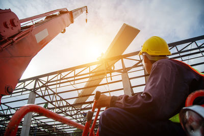 Asian crane drivers are steering cranes to install metal sheet, industrial roof installation.