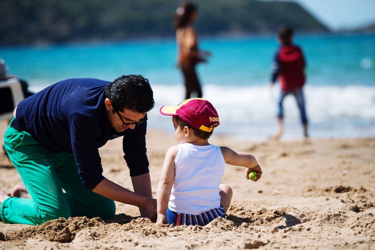 lifestyles, leisure activity, beach, togetherness, sand, childhood, boys, casual clothing, focus on foreground, rear view, full length, bonding, men, love, girls, shore, person, family with one child