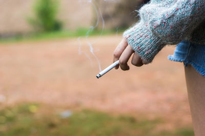 Cropped image of woman smoking cigarette outdoors
