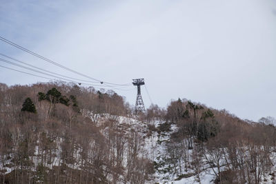 Electricity pylon by snowcapped mountain against sky