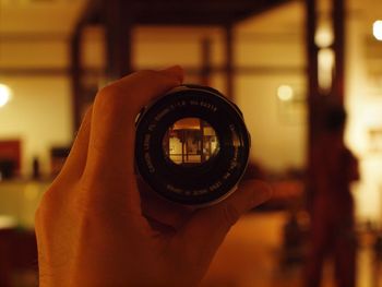 Cropped image of person holding camera lens at home
