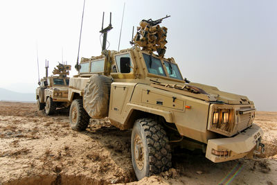 Scene depicting military armored vehicles navigating through arid desert terrain. 