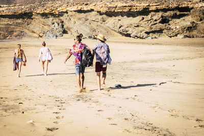 Rear view of friends walking at beach