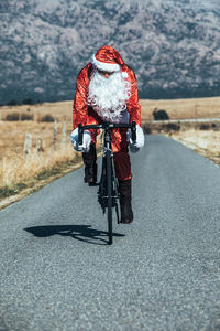 Rear view of man riding bicycle on road