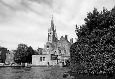 Monochrome image of canal cruise in historic centre of brugge with the church of our lady, belgium