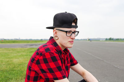 Young man wearing glasses on field against clear sky