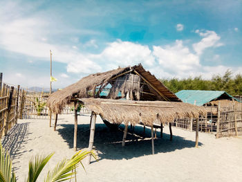 Stilt house on beach against sky