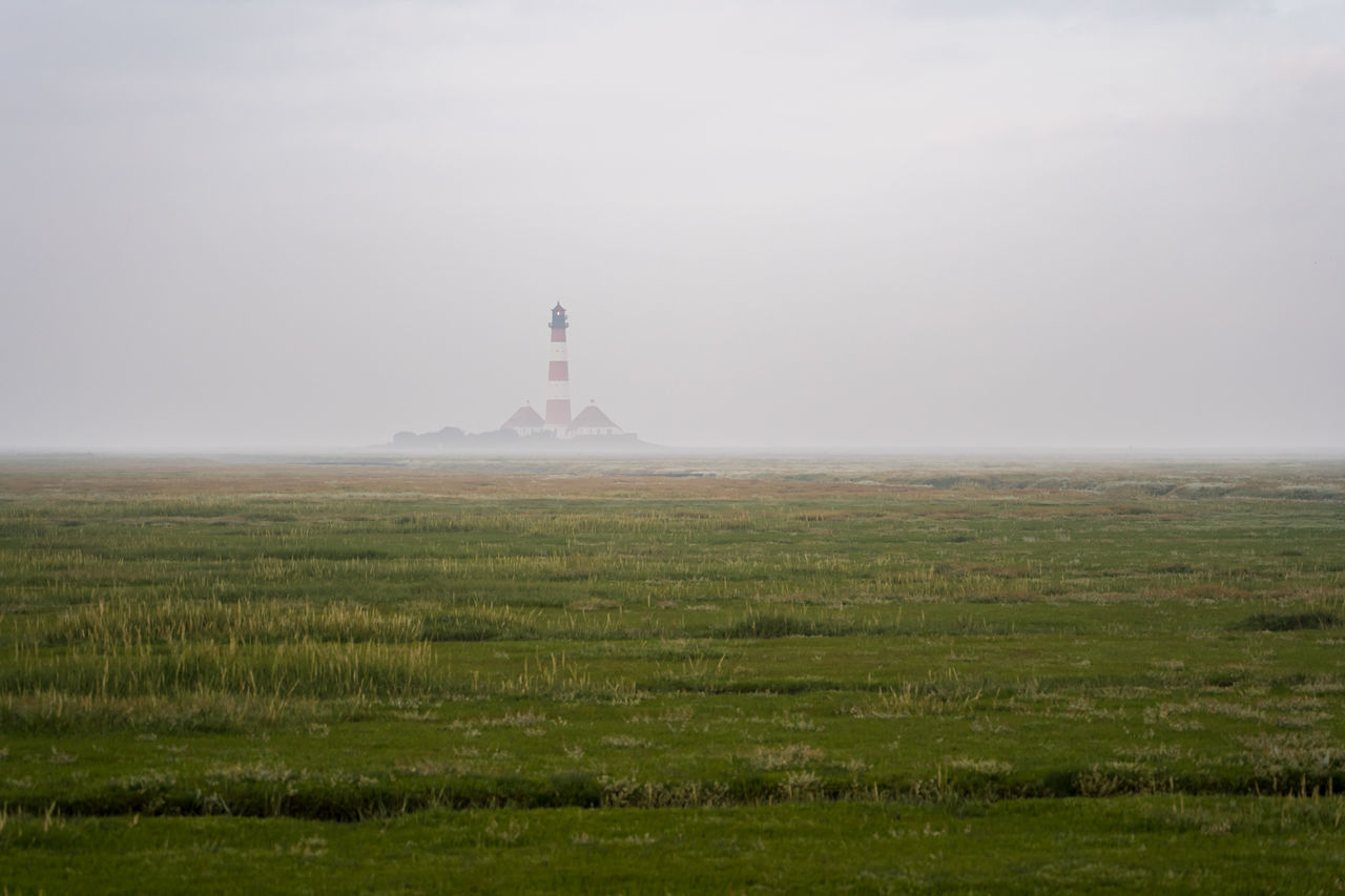 horizon, tower, environment, landscape, plain, sky, fog, hill, architecture, nature, travel destinations, grass, travel, plant, built structure, land, natural environment, sea, no people, scenics - nature, mist, tourism, rural area, field, morning, beauty in nature, prairie, outdoors, history, copy space, building exterior, tranquility, building, wind, cloud, the past, tranquil scene, day, lighthouse, non-urban scene, distant, social issues, green, wetland, coast