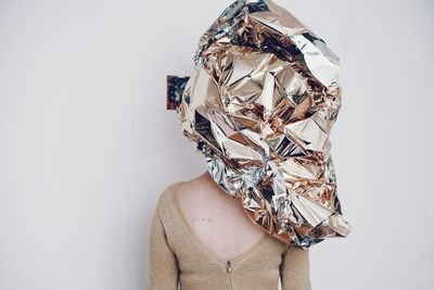 Rear view of woman covered in wrapping paper against white wall