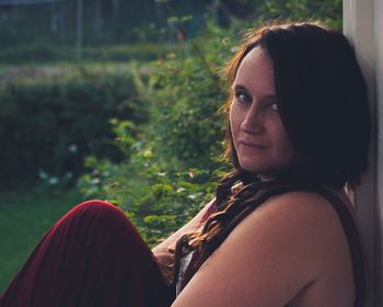 Portrait of mature woman sitting by wall