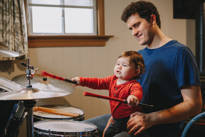 Son playing drums while sitting with father at home