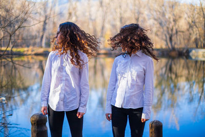 Sisters with tousled hair standing by lake