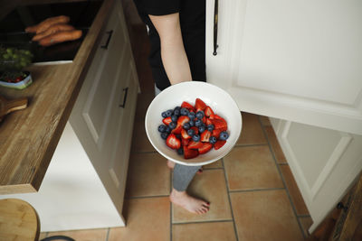 High angle view of woman holding fruits in bowl