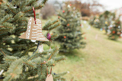 Handmade brown cardboard paper christmas bell decoration on christmas tree, outdoors. diy