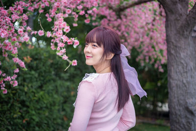 Beautiful woman standing by pink flowering plants