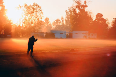 Silhouette man photographing at sunset