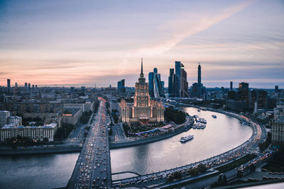 Aerial view of river amidst buildings against sky during sunset