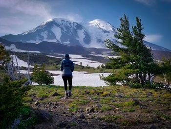 Rear view of woman standing on mountain against sky