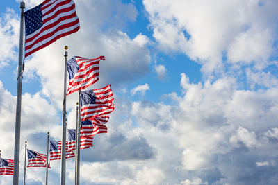 Low angle view of american flags against cloudy sky