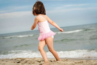 Full length of girl standing at beach against sky