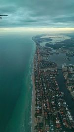 Aerial view of city by sea against sky
