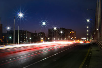 Light trails on street against sky at night