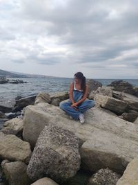 Woman sitting on rock at beach