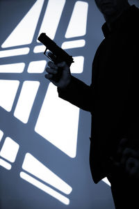 Low angle view of man holding umbrella standing against wall